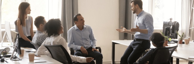 A diverse team of six gather in an office in conversation