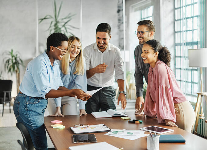 Group of people actively engaging in teamwork standing around a desk