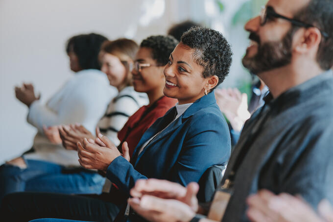 People sitting down clapping at an event