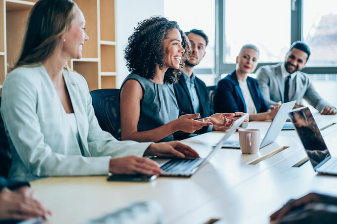 A group of people sitting in a boardroom working and talking