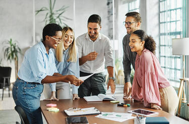 Group of people actively engaging in teamwork standing around a desk