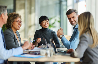 Group of people engaging in a meeting sitting around a table