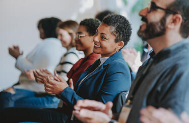 People sitting down clapping at an event