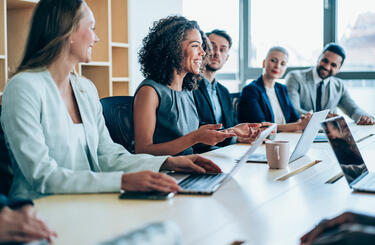 A group of people sitting in a boardroom working and talking