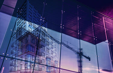 Construction crane and a new high rise building reflected into a newly built office building. 