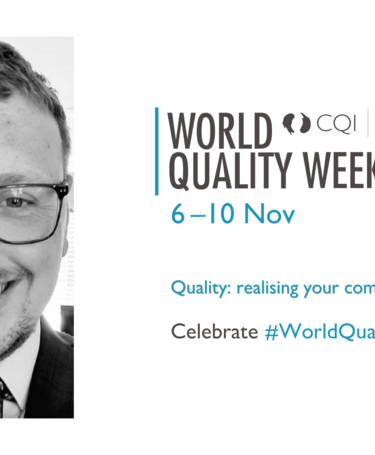 Mitchell Reed is pictured smiling in a suit and tie wearing glasses. The World Quality Week logo is to the right
