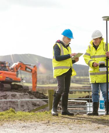 Construction workers examine a tablet