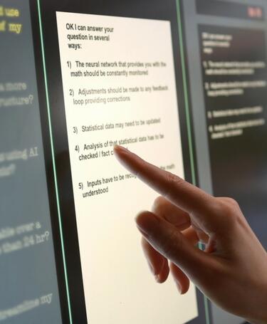 Large computer screen with finger pointing to text.