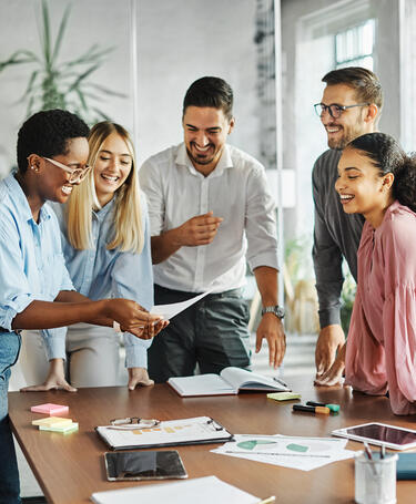 Group of people actively engaging in teamwork standing around a desk