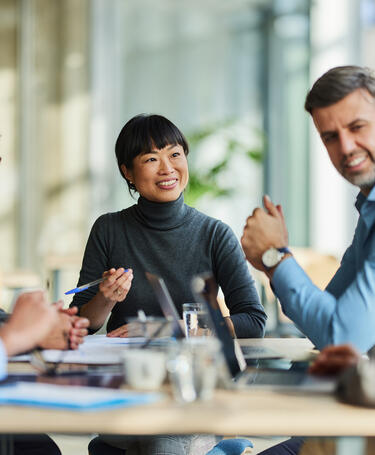 Group of people engaging in a meeting sitting around a table