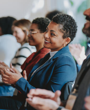 People sitting down clapping at an event