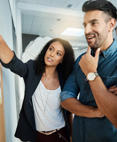 Three people standing up working together discussing concepts on a wall in an office
