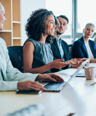 A group of people sitting in a boardroom working and talking