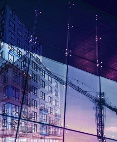 Construction crane and a new high rise building reflected into a newly built office building. 