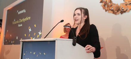 Victoria Derbyshire, young woman in black suit, speaking at the International Quality Awards 2022 event