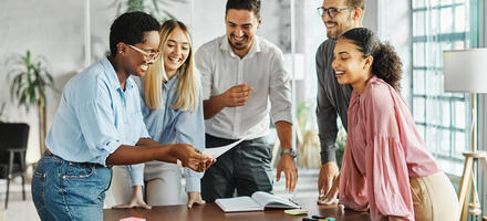 Group of people actively engaging in teamwork standing around a desk
