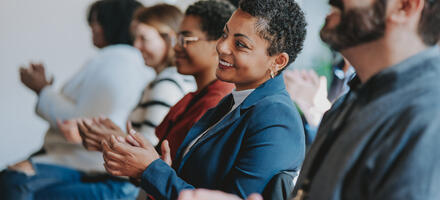 People sitting down clapping at an event