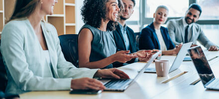A group of people sitting in a boardroom working and talking